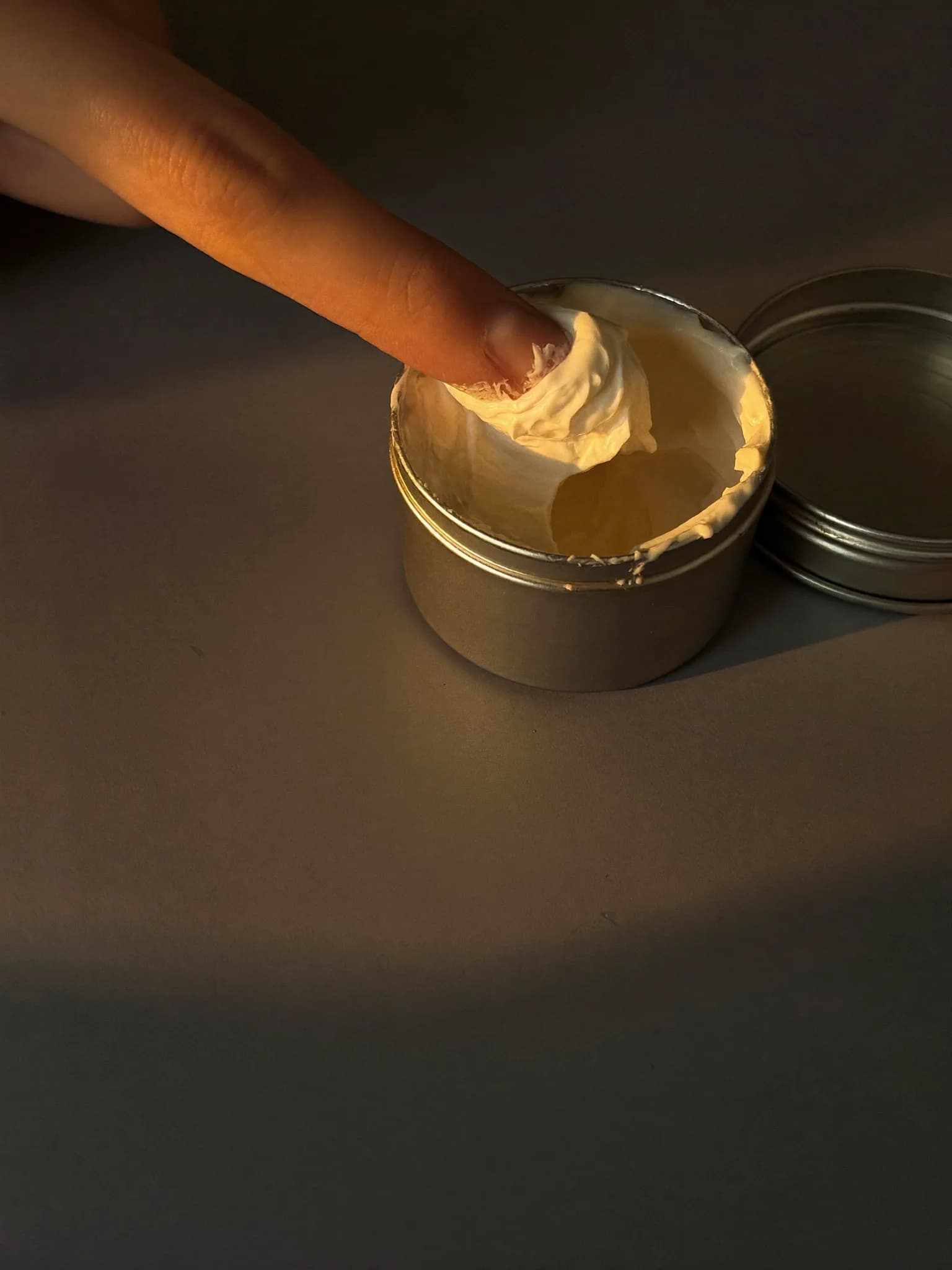 Fingertips scooping a little body butter from the tin